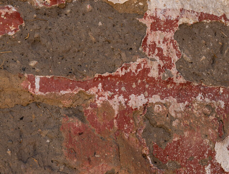 Weathered red painted wall with peeling paint, exposed cement and cracked plaster texture, distressed rustic surface, aged architectural background for construction, restoration and graphic design pro