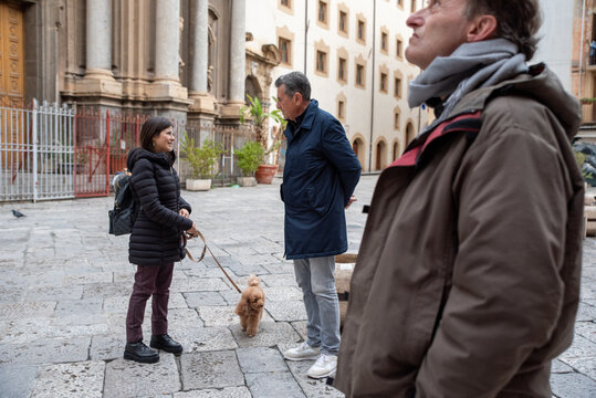 Two People in Palermo Converse While a Dog Waits in a Historic Square