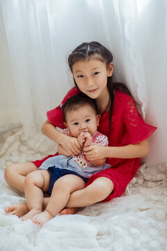 An Asian girl playing indoors with her baby.