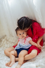 Fototapeta premium An Asian girl playing indoors with her baby.