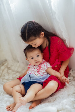 An Asian girl playing indoors with her baby.