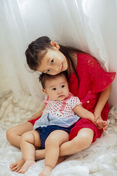 An Asian girl playing indoors with her baby.