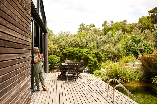 A Woman Stands on a Wooden Deck Holding a Cup