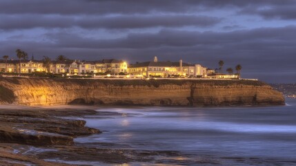 Obraz premium Wide evening view of seaside village stacked above rocky blue water at a glowing sunset