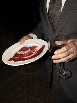 Guest Enjoying Red Wine and Cured Ham