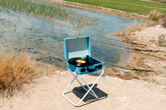beside a rice field, a turntable spins a vinyl in summer calm