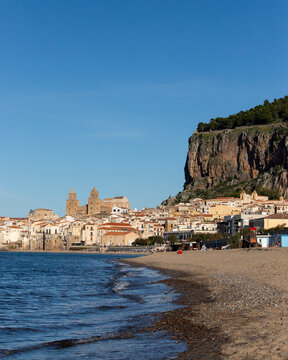 Cefalu Sicily coastal town with medieval cathedral and rocky cliff overlooking the sea and the beautiful beach in the mediterranean sea.