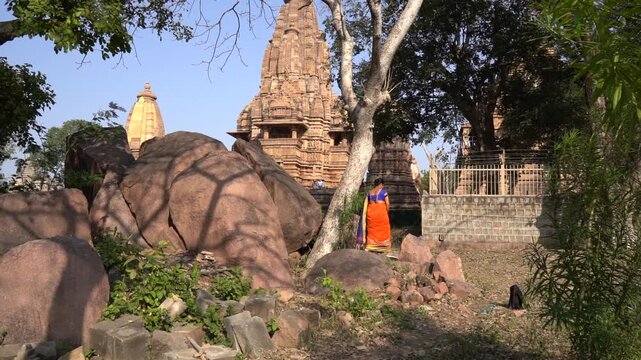 Indian woman in colorful saree walks around and explore Khajuraho Temple, UNESCO World Heritage Site, India.