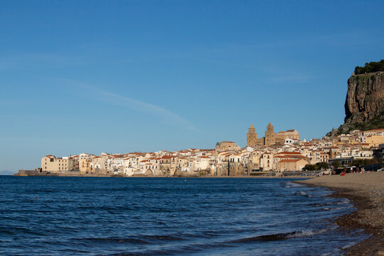 Cefalu Sicily coastal town with medieval cathedral and rocky cliff overlooking the sea and the beautiful beach in the mediterranean sea.