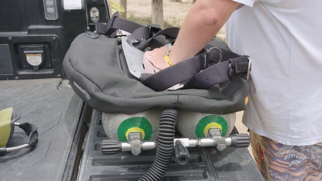 Scuba diver preparing and checking his technical diving equipment on the back of a pickup truck