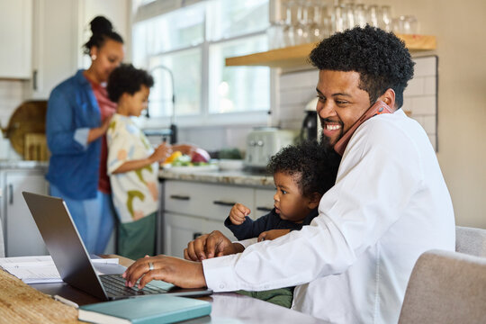 Father Works on Laptop While Caring for Baby