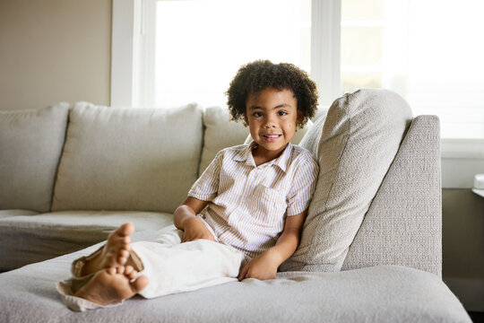 Child Sits on a Couch in a Living Room