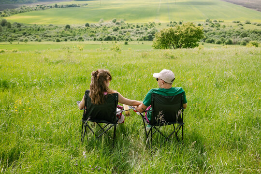 A man and a woman are relaxing on a green field.