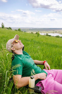 A man is resting on a chair on a green hill.