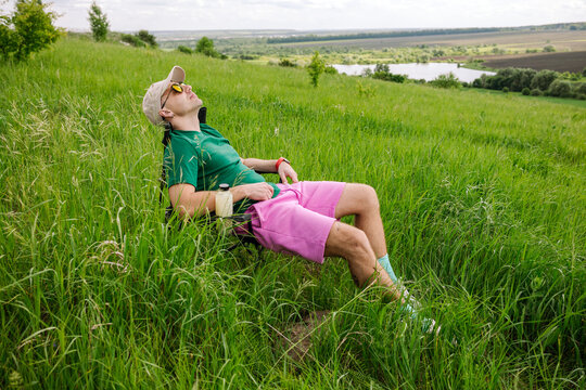 A man is resting on a chair on a green hill.