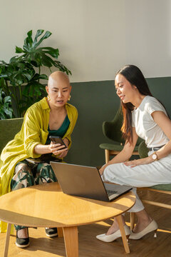 Women Discussing Work at a Table With a Laptop in a Coworking Space
