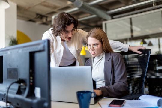 Business colleagues collaborating on laptop in modern office
