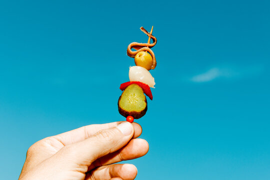 a spanish banderilla is held by a man against the blue sky