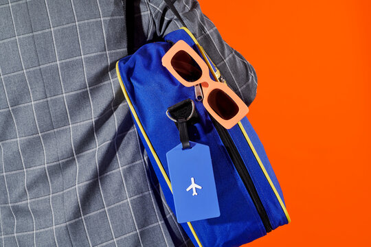 a man seen from behind carrying a blue travel bag