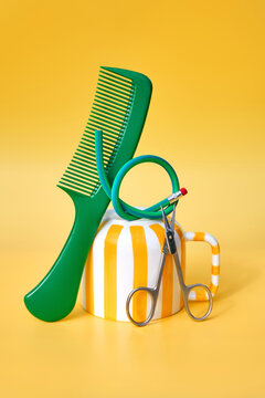 Comb and Flexible Pencil Balanced on Striped Mug on Yellow Background