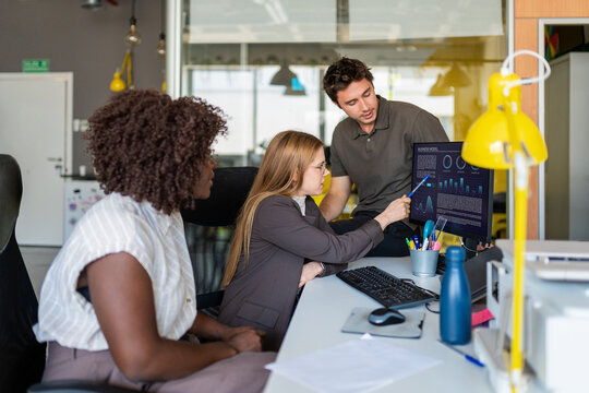 Business professionals discussing data on computer screen