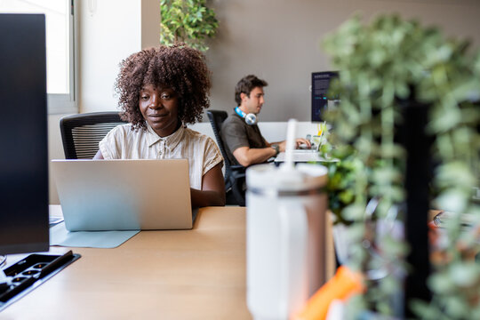 Black woman developer coding on laptop in modern office