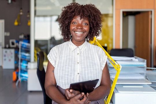 Black businesswoman smiling holding tablet in office