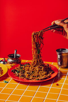 Person eating beef stir fry noodles with chopsticks 