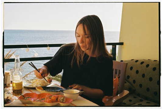 Woman Eating with Chopsticks on Oceanfront Balcony, Funchal