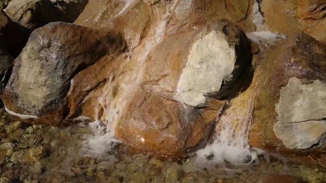decorative artificial stone waterfall fountain with flowing water in the courtyard of a modern alpine style resort. Beautifully designed hotel territory featuring wooden chalet buildings, outdoor
