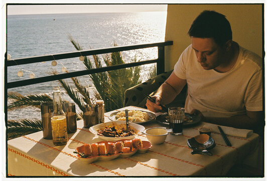 Man Dining on Balcony at Sunset with Ocean View, Funchal