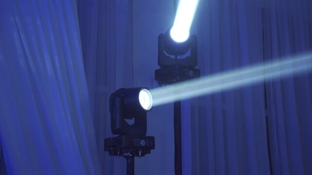 Moving white beams on stands during a disco. Stage lighting. A stand with lighting equipment, spotlights. Lighting equipment. Disco in a nightclub.