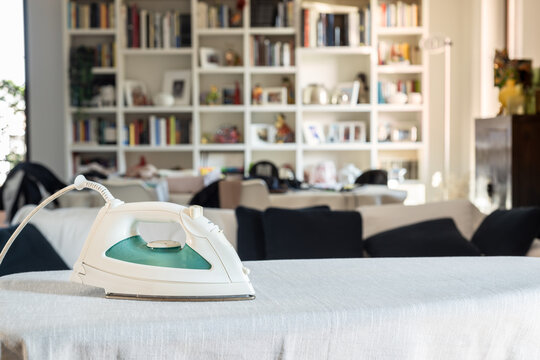 Modern iron on ironing board at home.