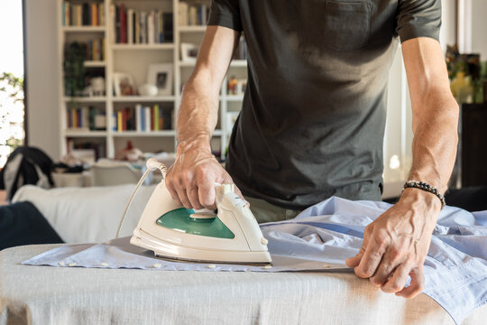 Front view of a man ironing shirt at home on sunny day.