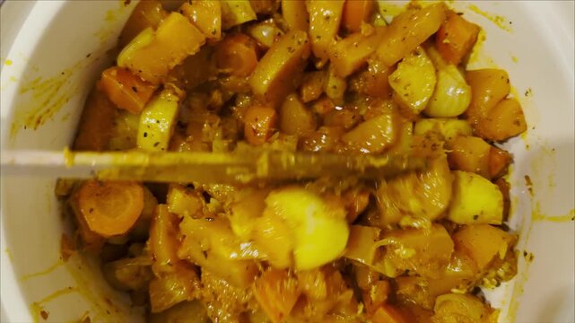 Top view on female hand stirs with spatula stew in pot on stove at kitchen. The mixture of meat and vegetables cooks evenly releasing rich aroma. Focus on appetizing appearance of hearty homemade dish