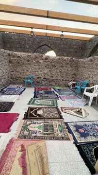 Prayer mats arranged in the historic open-air stone courtyard of Masjid Bani Anif.