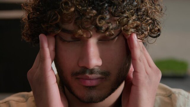 Close up Indian business man massaging temples headache at home indoors exhausted Arabian male freelancer sick suffering migraine blood pressure health problem stress businessman trouble burnout pain
