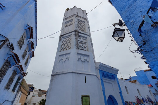White mosque minaret and iconic blue houses at historical town of Chefchaouen in Morocco