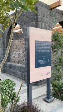 Courtyard, information sign, and stone arches of Masjid Bani Anif at sunset in Medina.