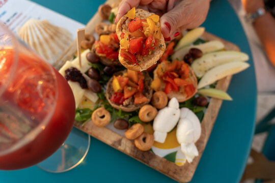 Hand holding fresh Italian bruschetta over Apulian appetizer board