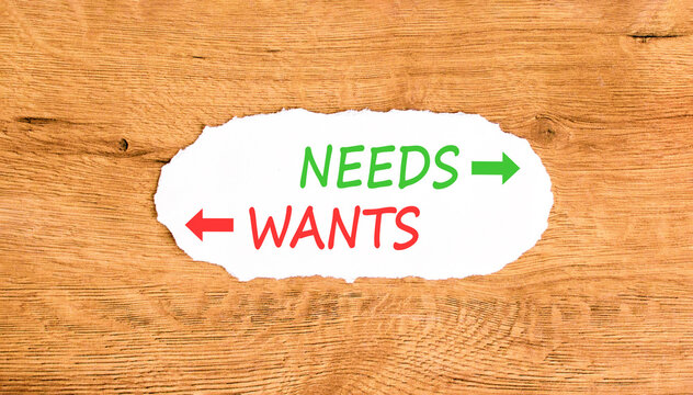Needs instead wants words symbol. Concept words Needs Wants on beautiful white paper. Beautiful wooden background. Business psychology needs or wants concept. Copy space.