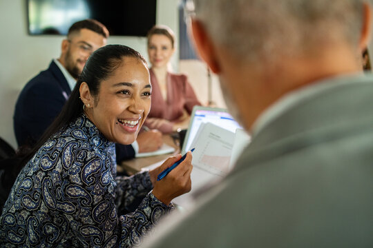 Smiling businesswoman discussing data with colleagues in modern office