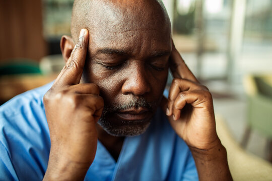 Stressed healthcare worker touching temples in clinic