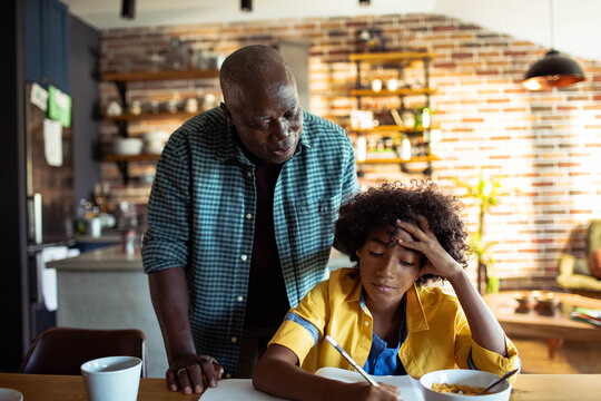 Senior man helping boy with homework at kitchen table