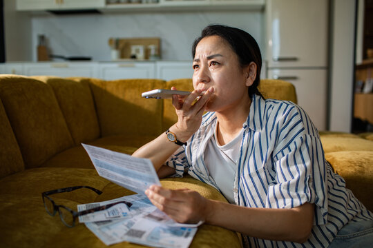 Woman reviewing bills and calling customer service at home