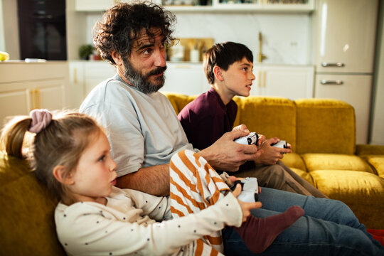 Father and kids playing console video games at home