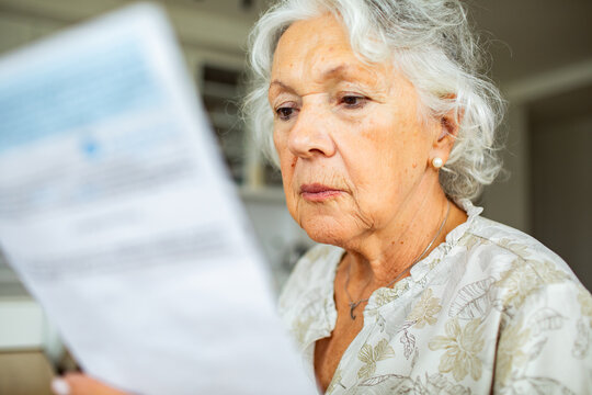 Senior woman reading bill at home
