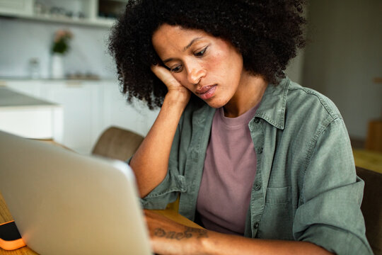 Woman stressed while working on laptop at home