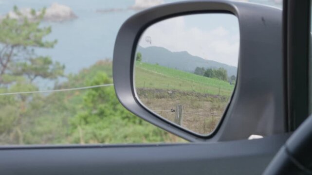 Driving along the asturian coastline viewing scenery in side mirror