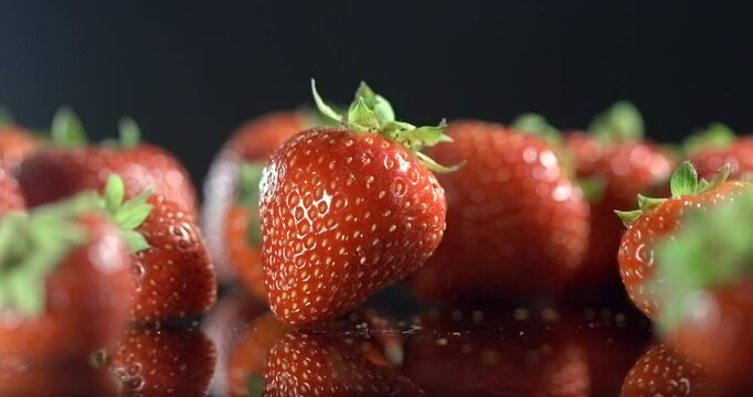 Strawberry falling among ripe strawberries on a black background in slow motion
